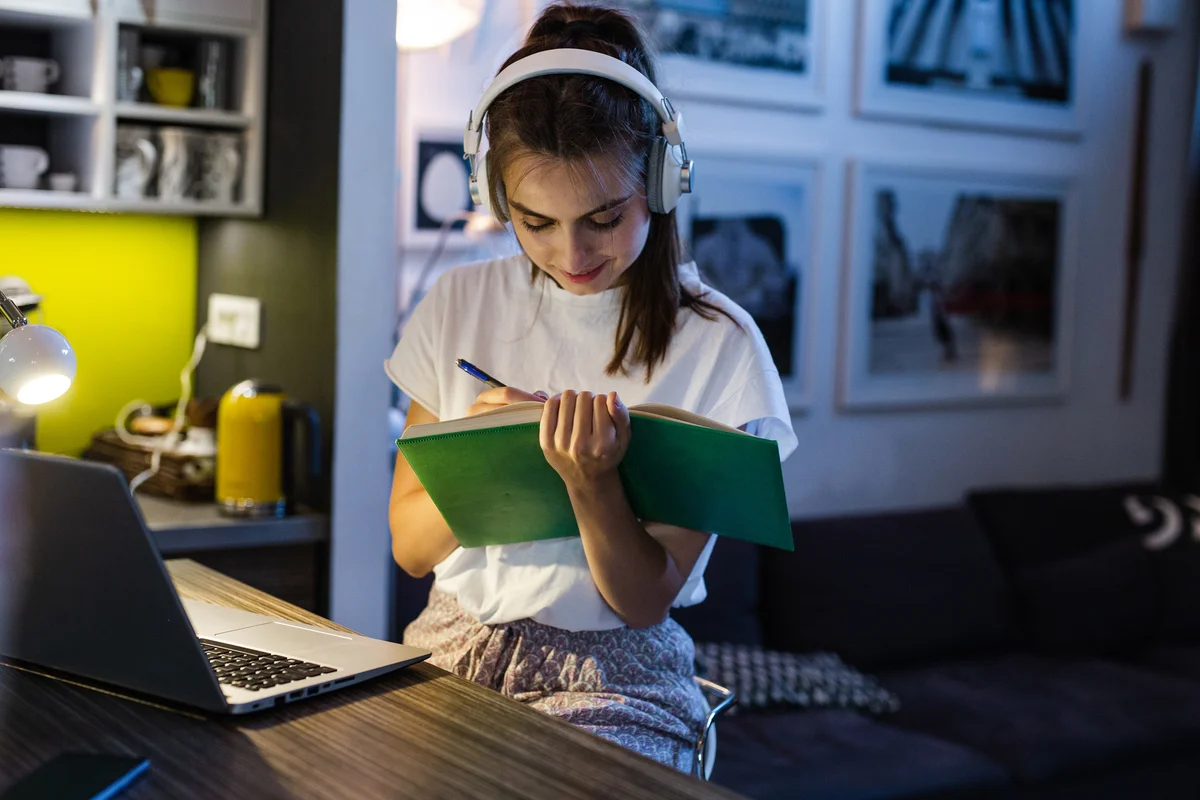 Teen girl studying while wearing noise-canceling headphones