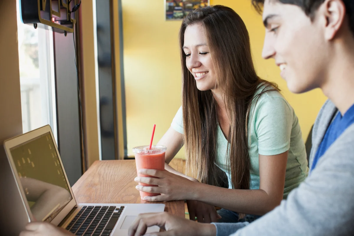 Two teens studying on laptop with smoothies