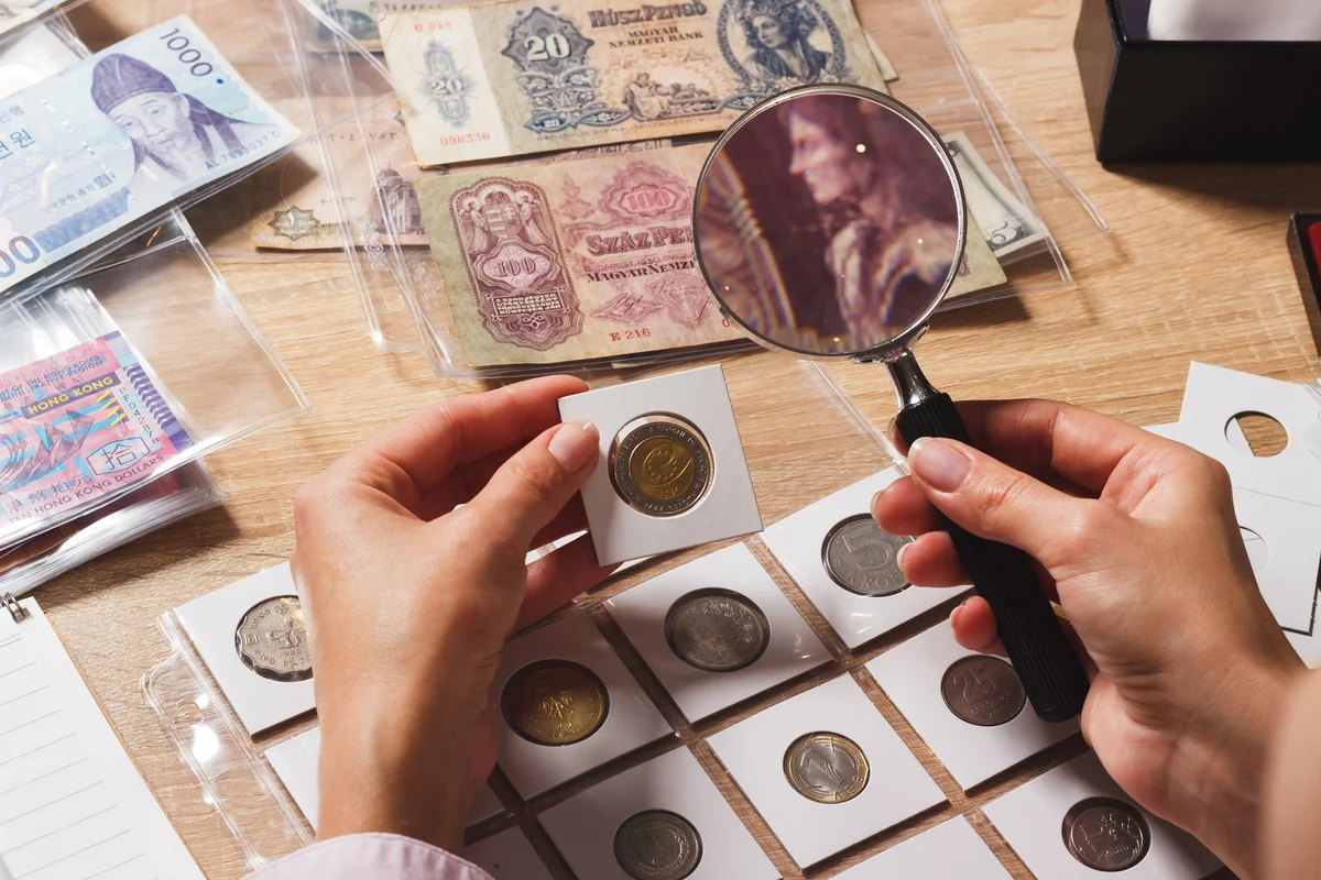 Woman using magnifying glass to inspect coin collection