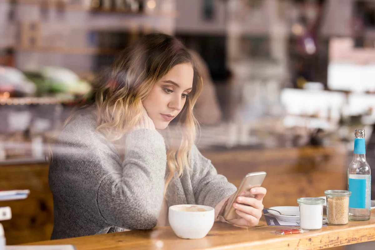 young woman in a coffee shop looking at cell phone