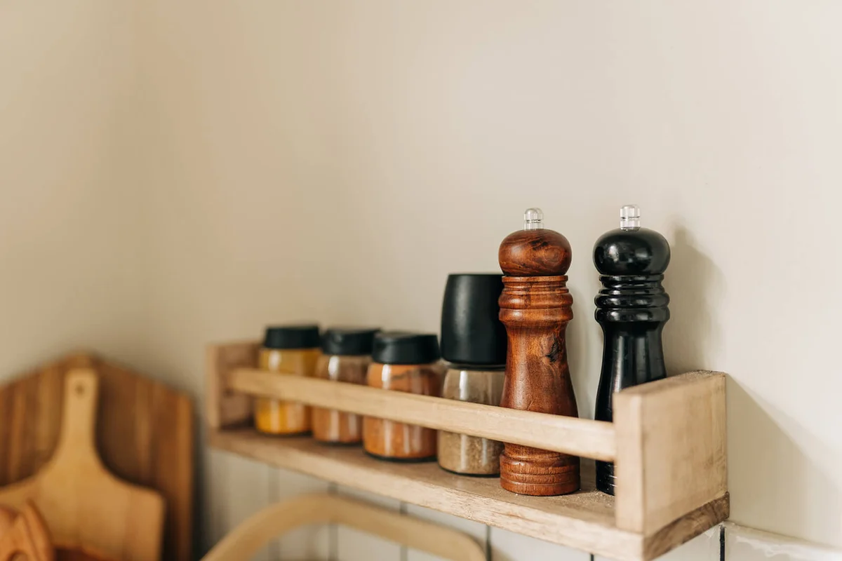 Spice jars on wooden shelf on a brick wall