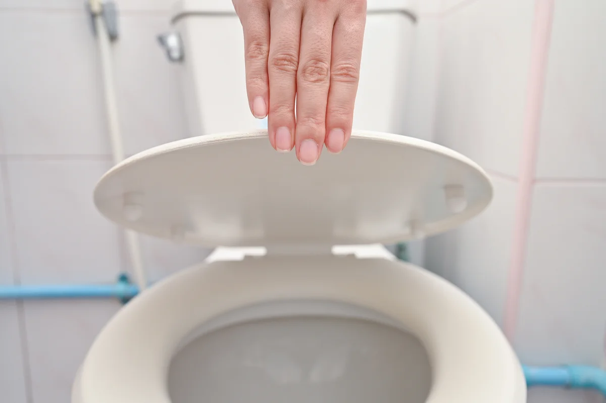 hand closing a toilet lid