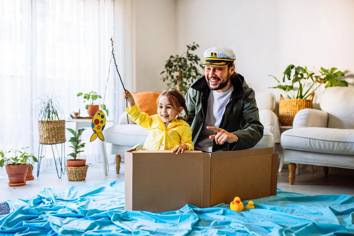 Little girl with father playing fishing at home