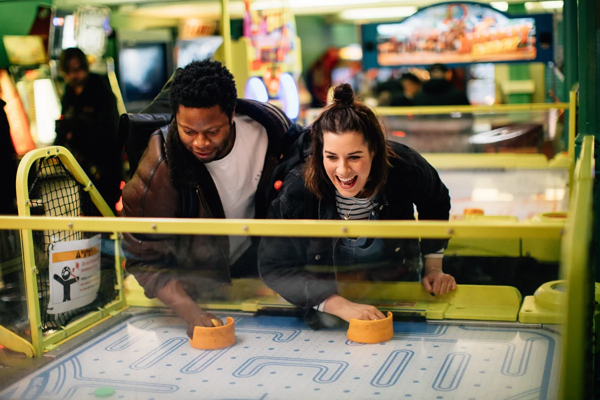 Couple having fun at arcade playing air hockey
