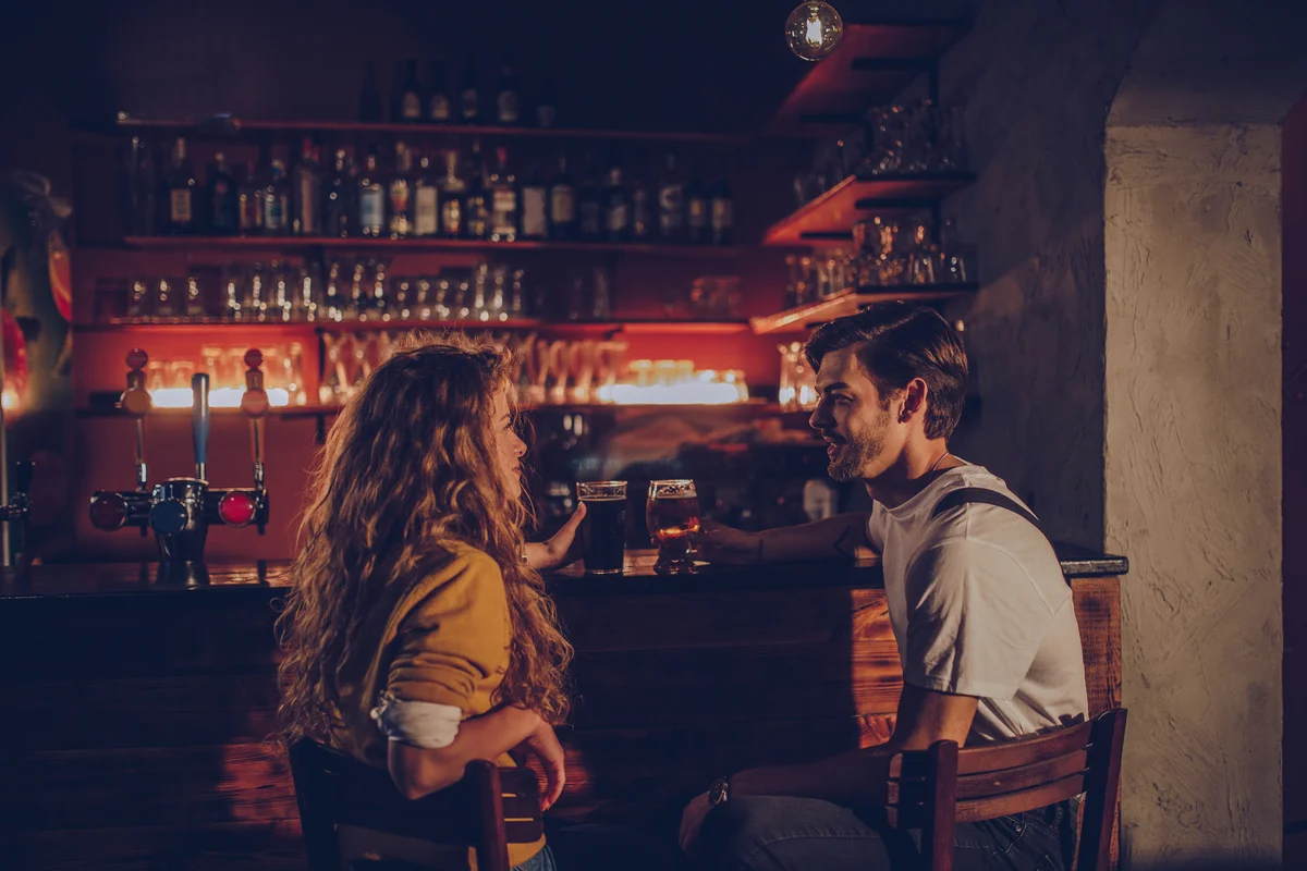 Couple enjoying drinks at the bar and talking to each other