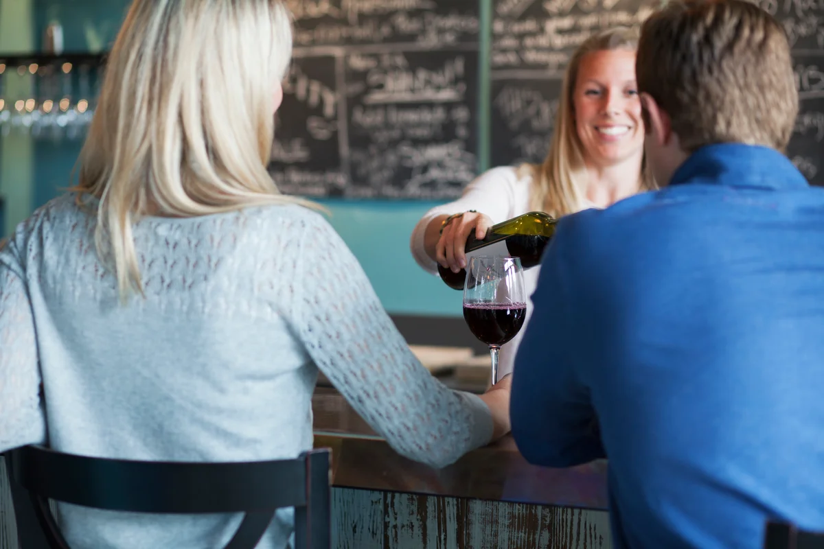 Couple in winery having glass of wine poured