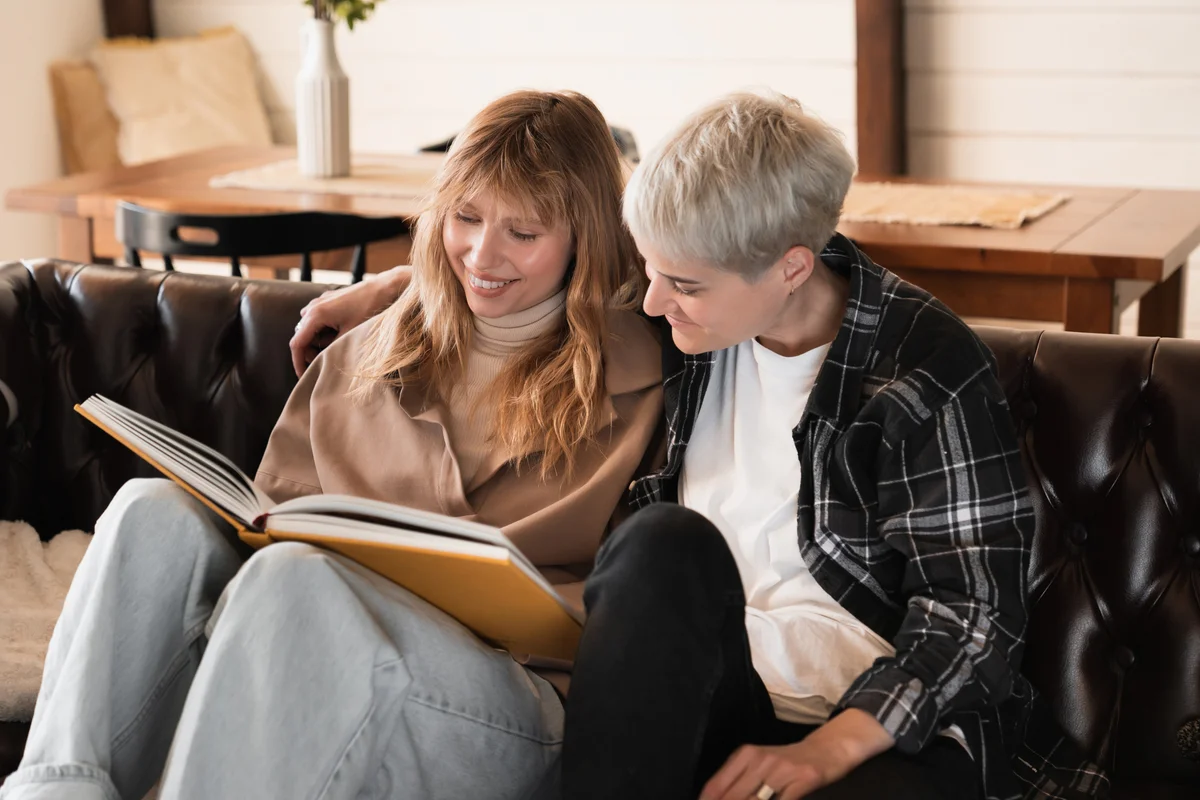 Two women cuddling and looking at scrapbook