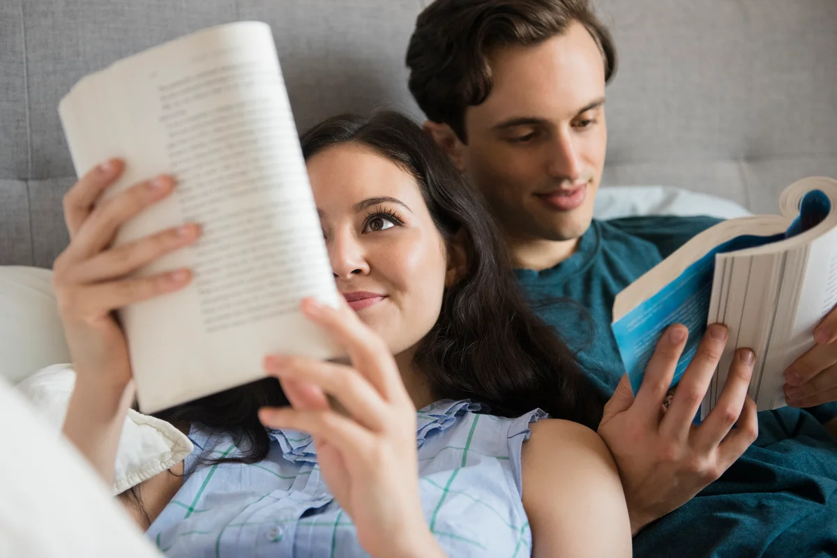 Couple laying next to each other and reading their own books