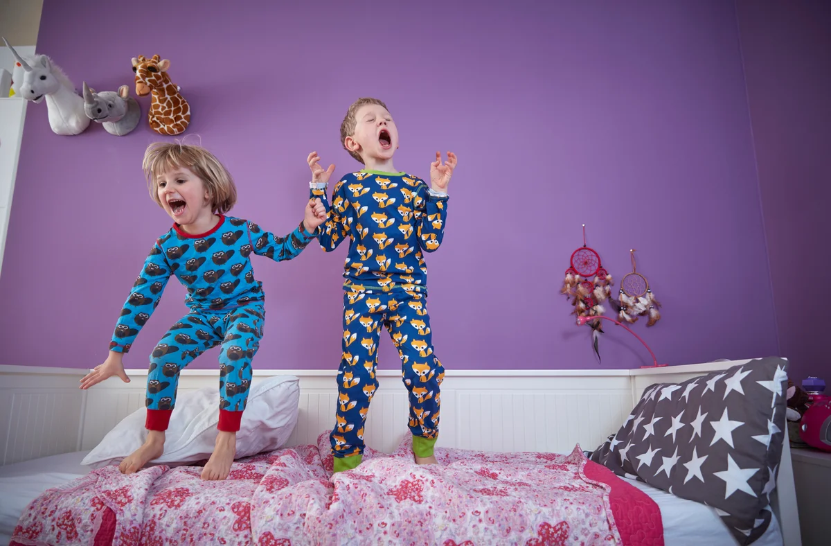 Energetic kids jumping on bed