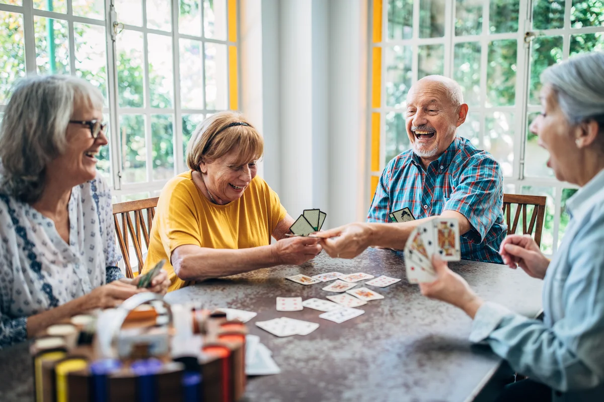 Group of seniors playing cards around table