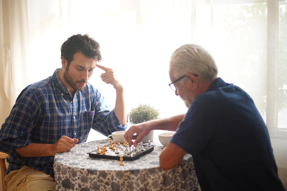 Senior father and adult son playing chess