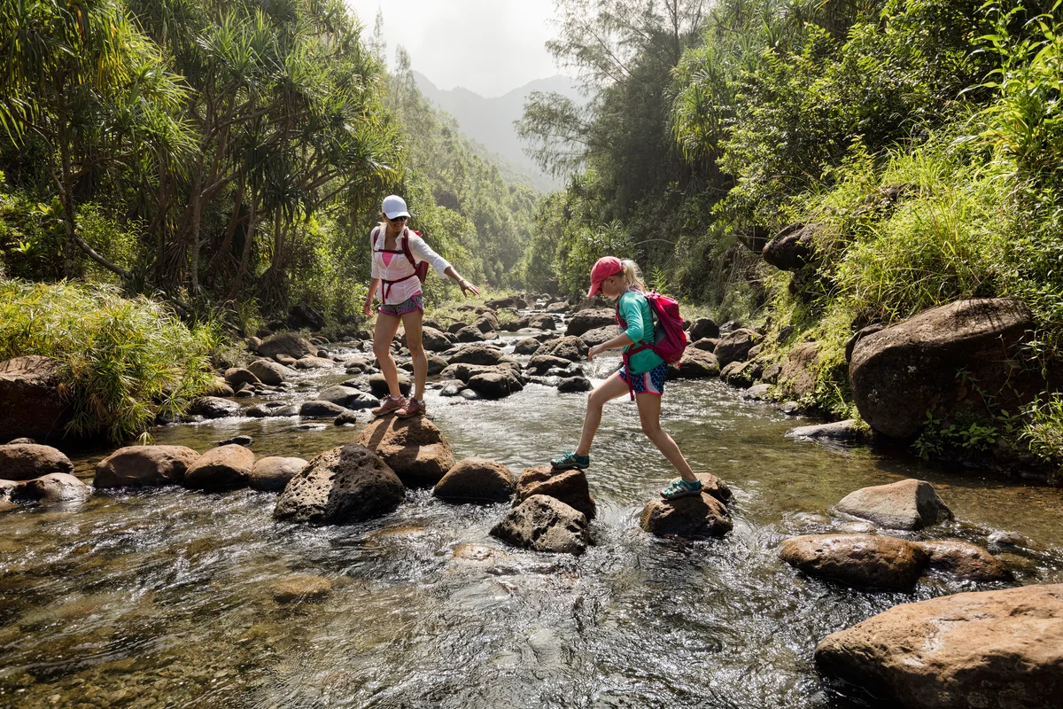 Mom and daughter hiking across river