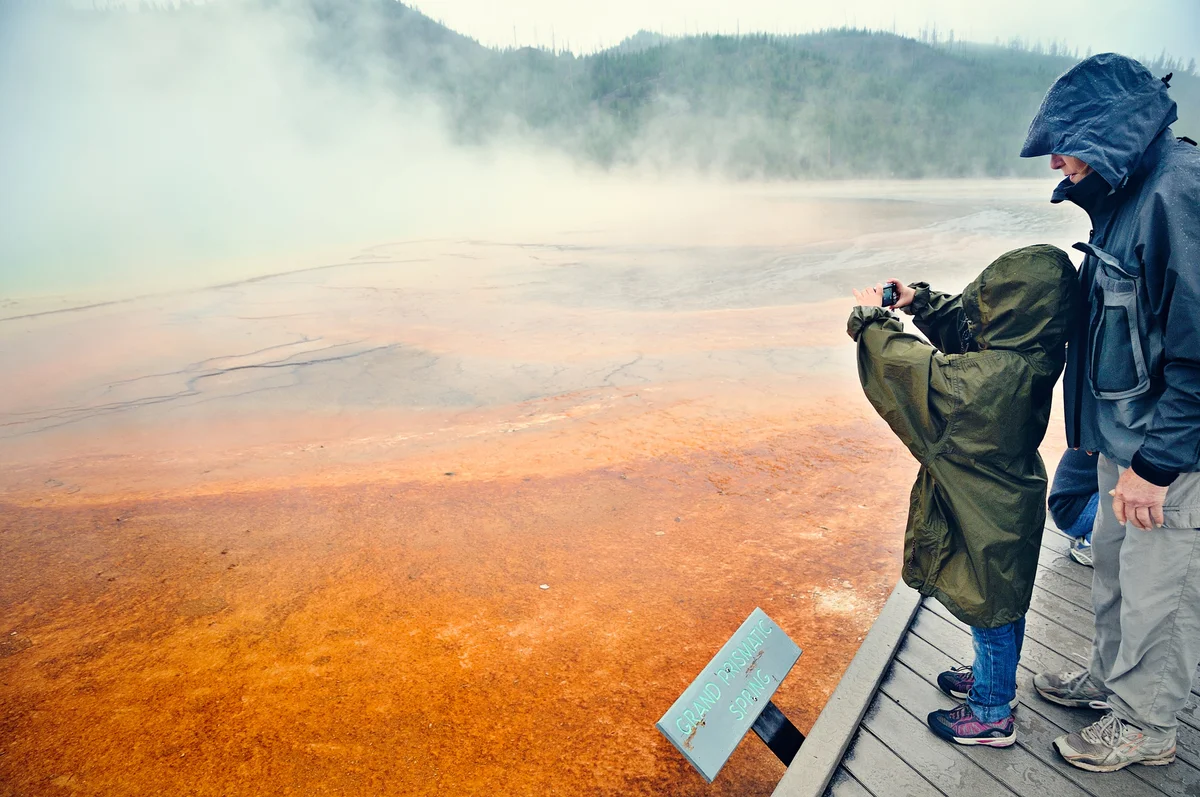 Dad and daughter taking photo of hot spring in Yelowstone