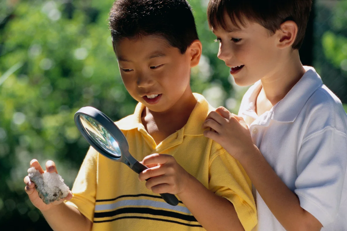 Boys studying cool rock with magnifying glass