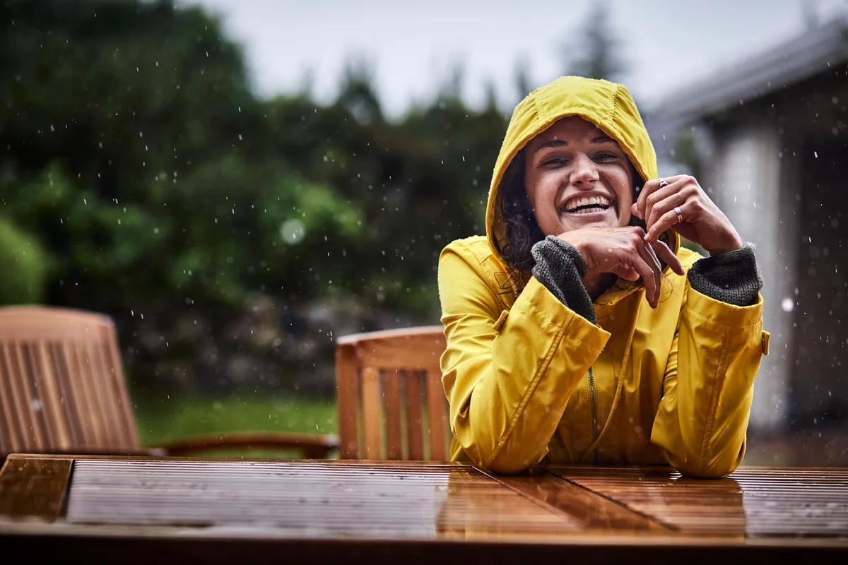 Woman in yellow raincoat smiling in the rain