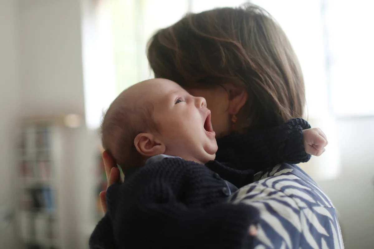 mother holding yawning baby