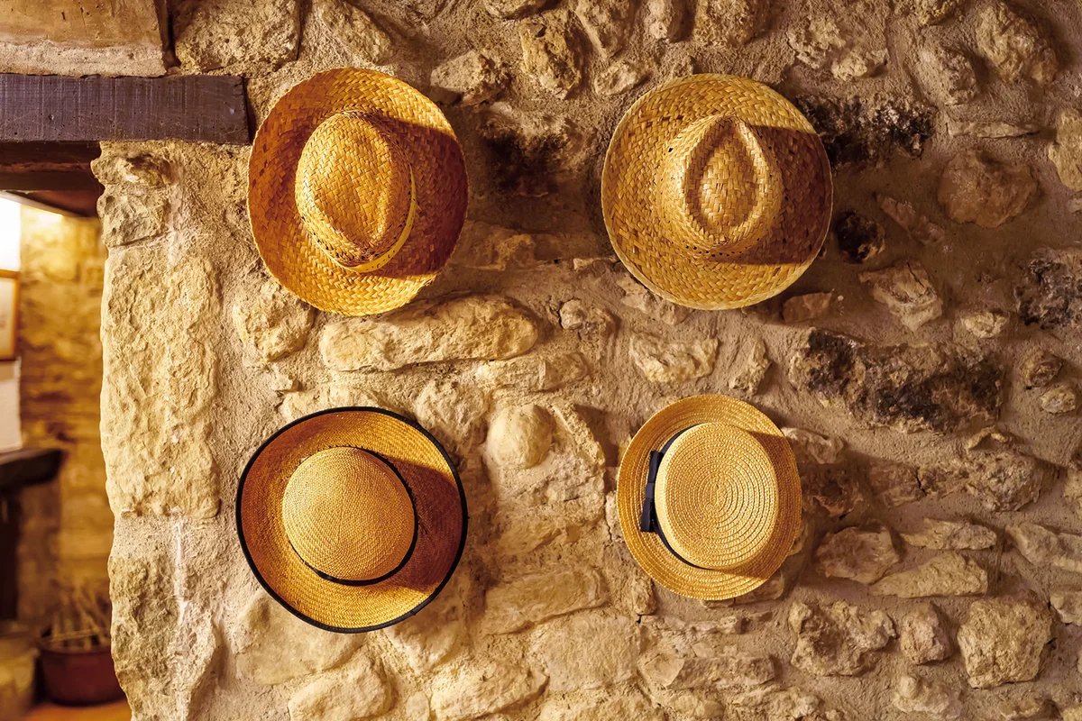 Straw hats hanging on the wall of an old retro-style house reminiscent of times gone by.