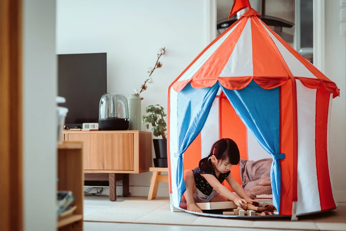 Little girl playing with toys in a tent at home