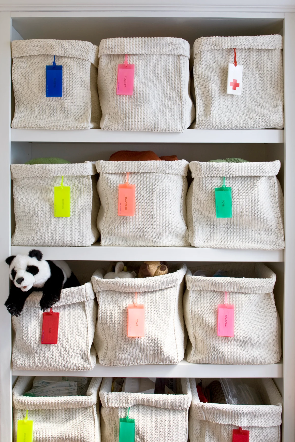White woven storage baskets with individual labels for organizing a child's bedroom