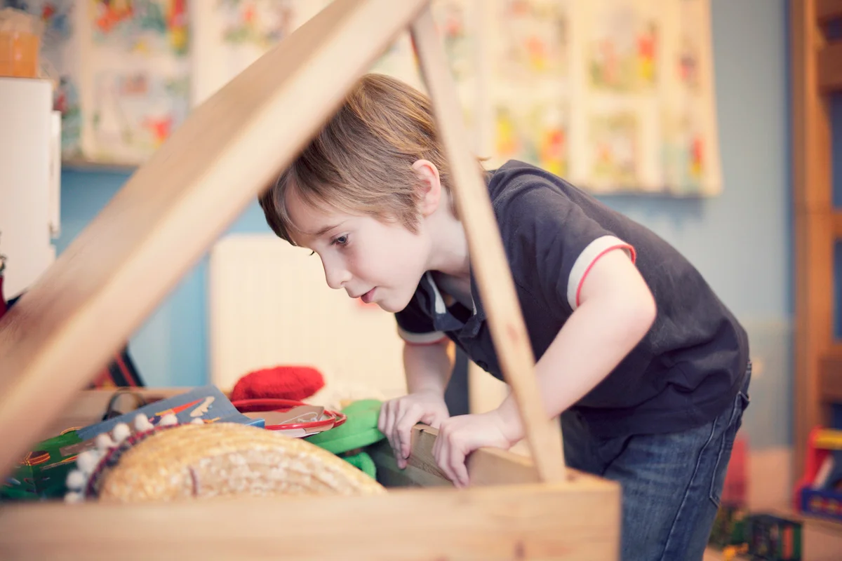 Young boy looking for toys in toy chest
