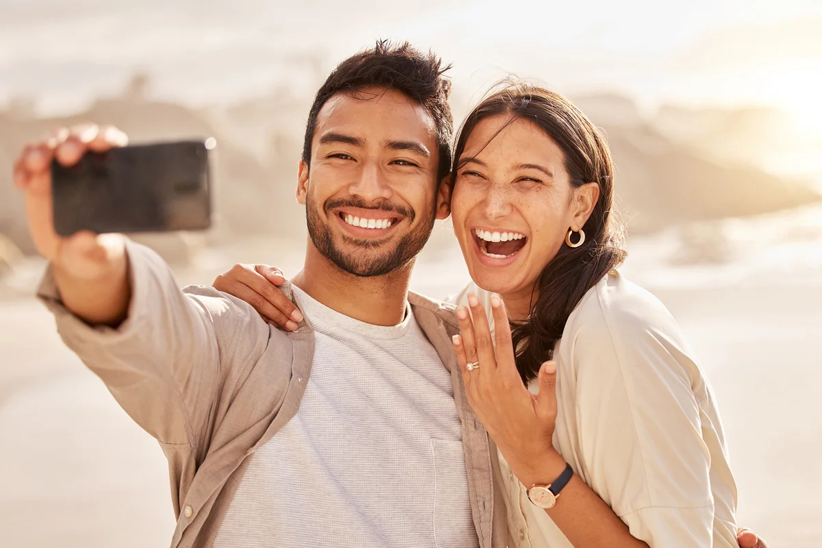 young couple taking selfies at the beach
