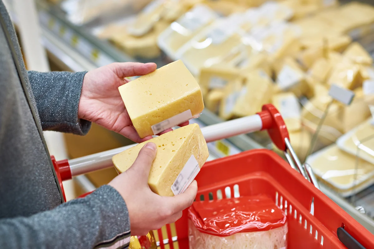 Hands with pieces of cheese in store