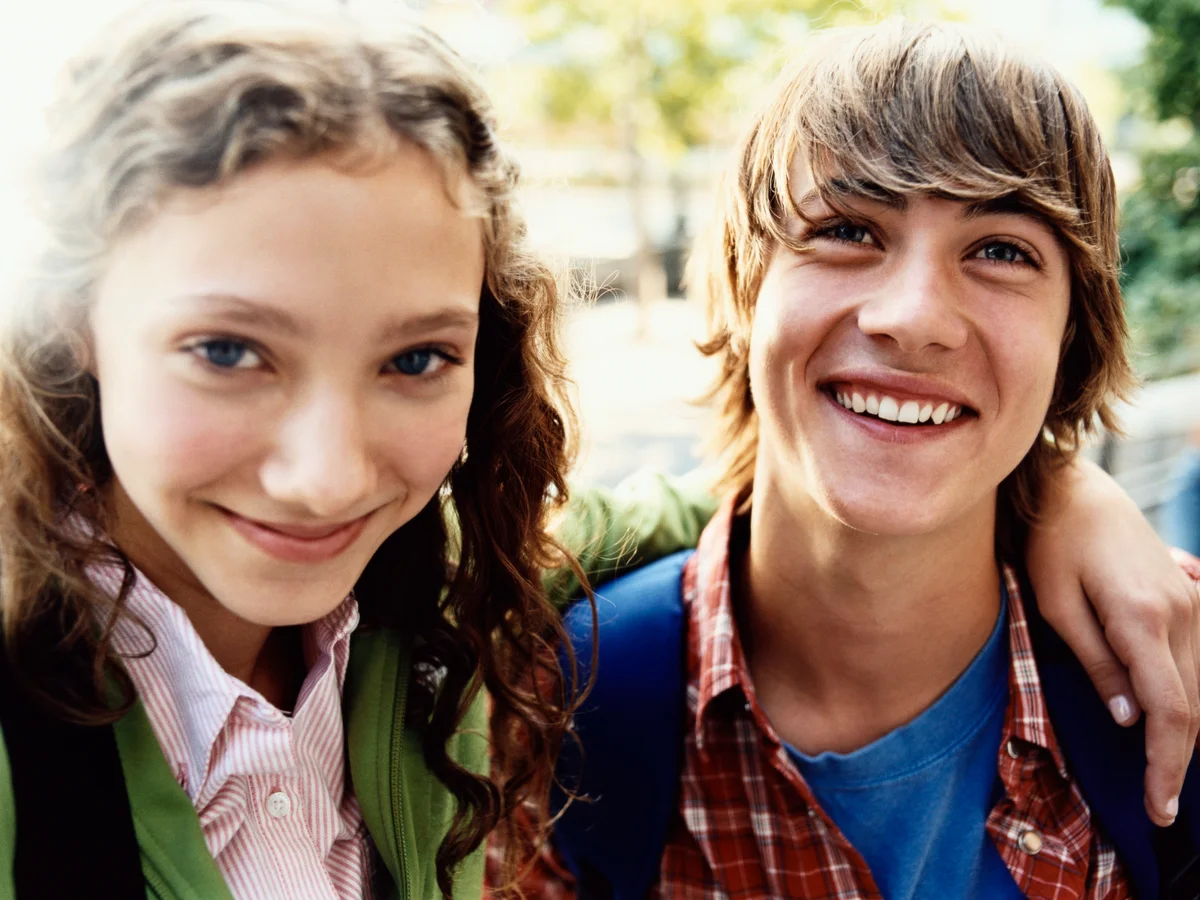 Young tween/teen couple with girls arm around boy