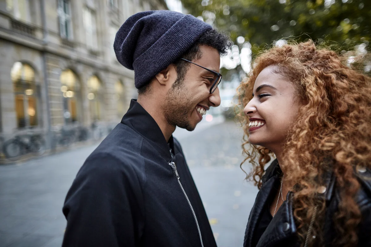 Beautiful young couple in their 20s in city, smiling at each other