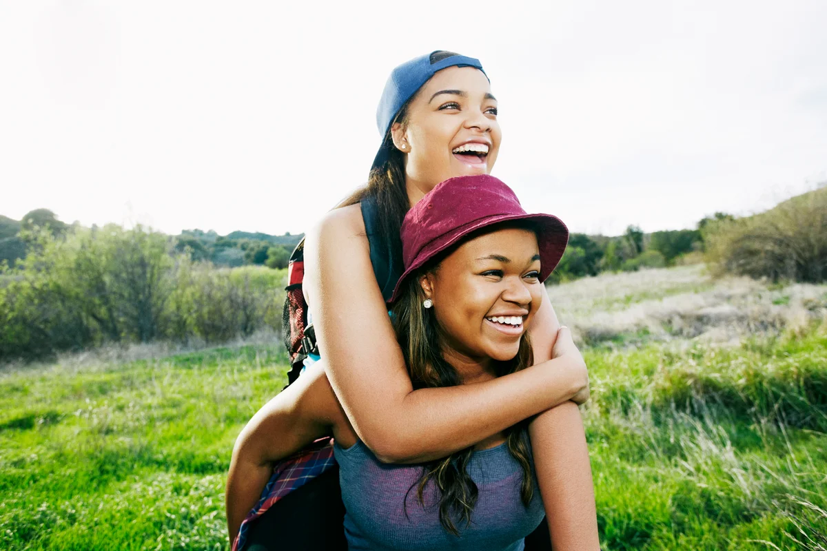 Young female couple giving piggyback ride outside