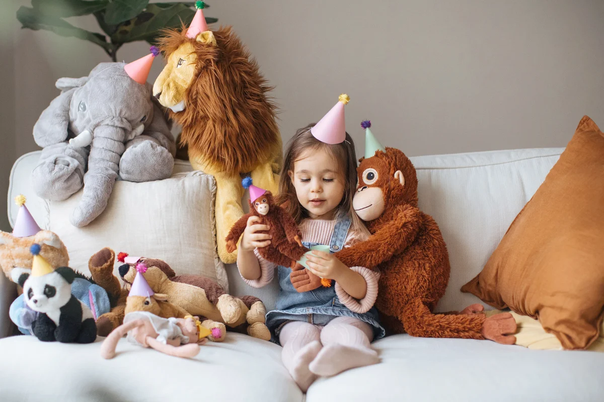 Little girl playing surrounded by stuffed animals