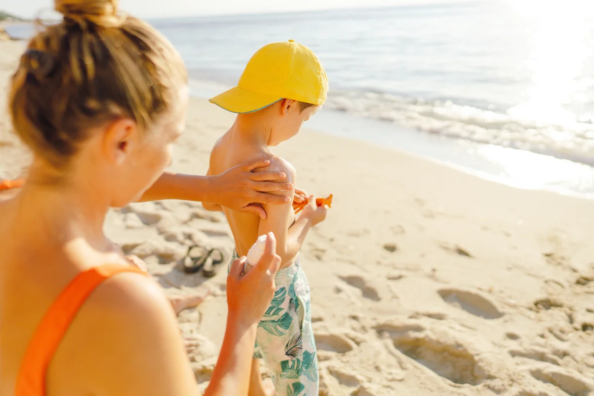 Mother applying sunscreen lotion on her son's skin