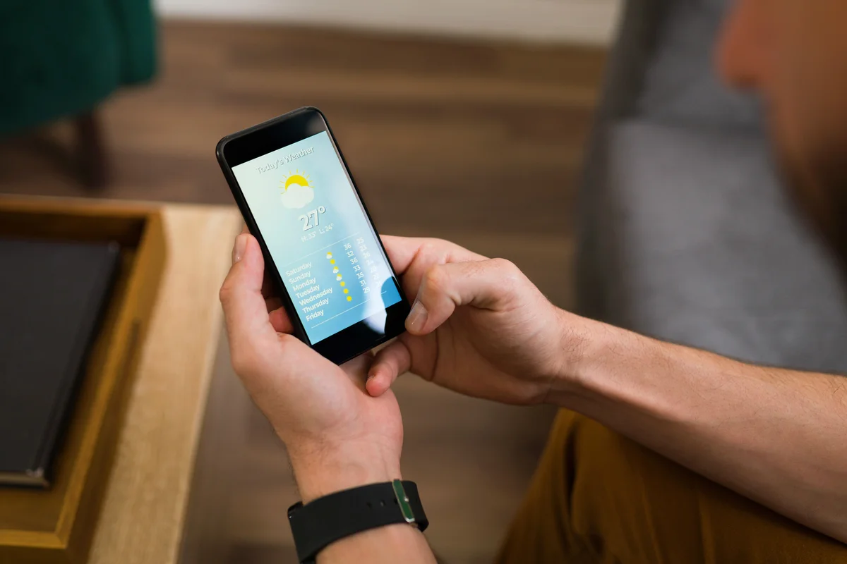 Man looking at the daily weather on his smartphone app