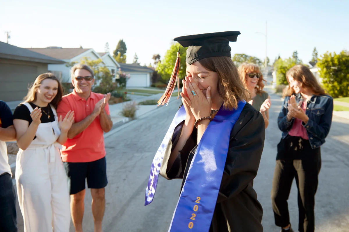 Young woman dressed in a graduation hat surrounded by her friends and family