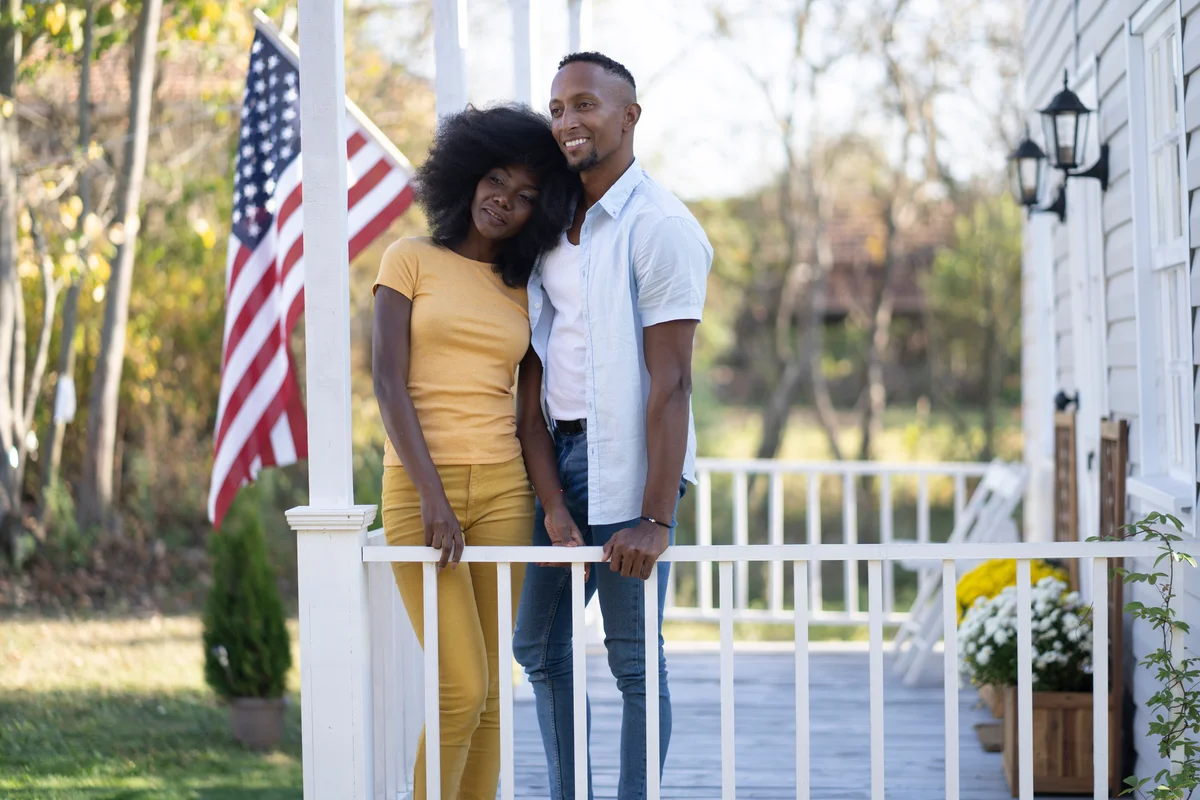 Couple standing on porch in front of American Flag