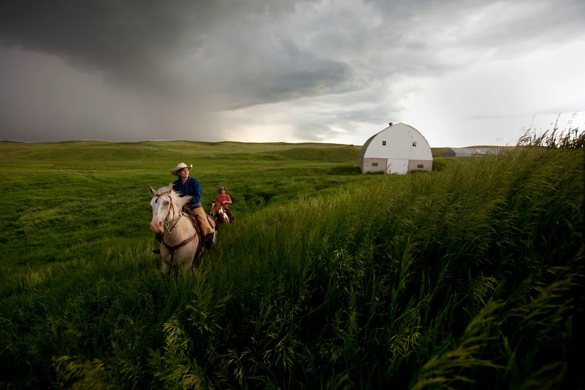 Couple riding horseback through Northa Dakota prairie