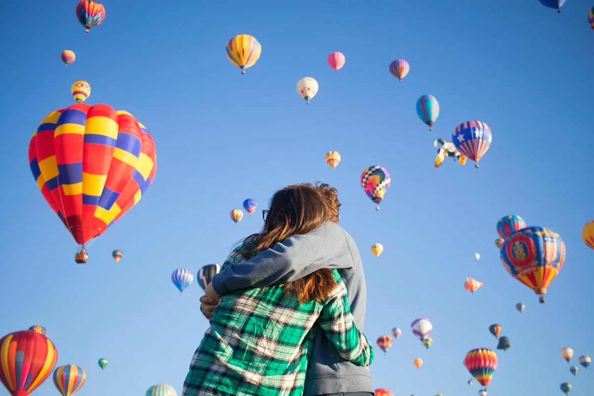 Couple hugging and watching hot air balloons in Oklahoma