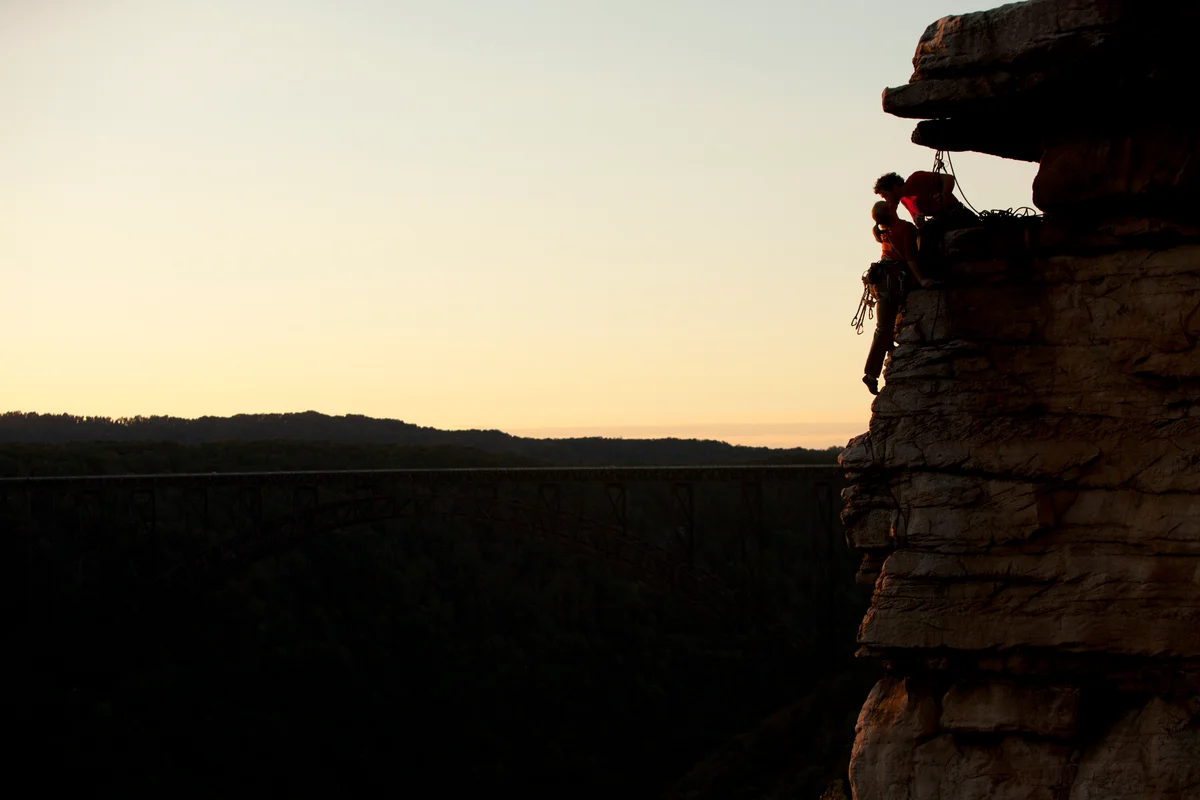 West Virginia couple rock-climbing and kissing on the mountainside