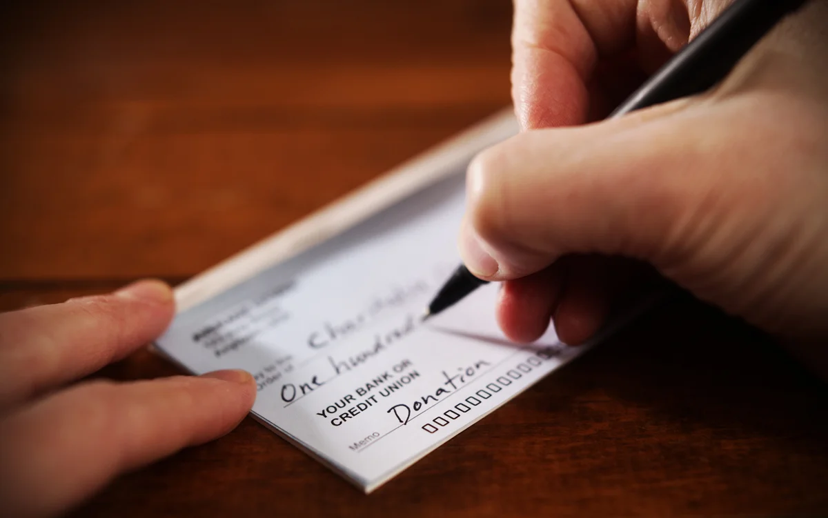 Closeup of person writing check for a donation