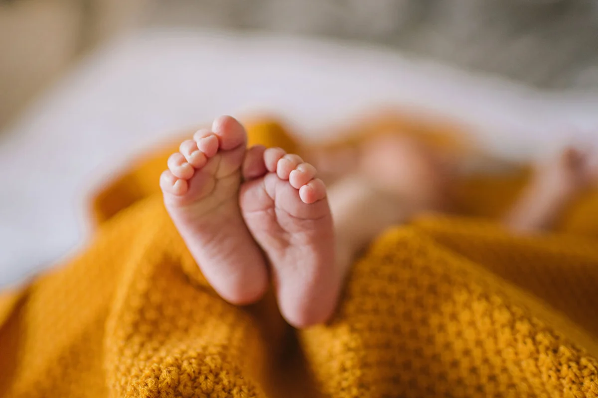 Tiny newborn baby feet in a yellow blanket