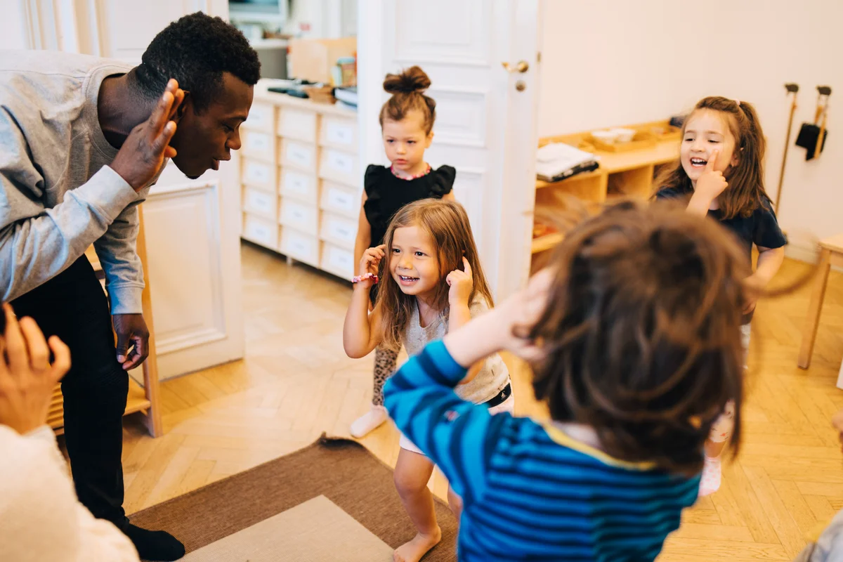 Male kindergarten teacher playing with kids