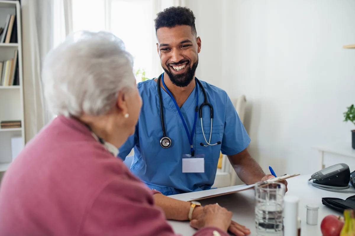 Nursing assistant smiling at elderly patient