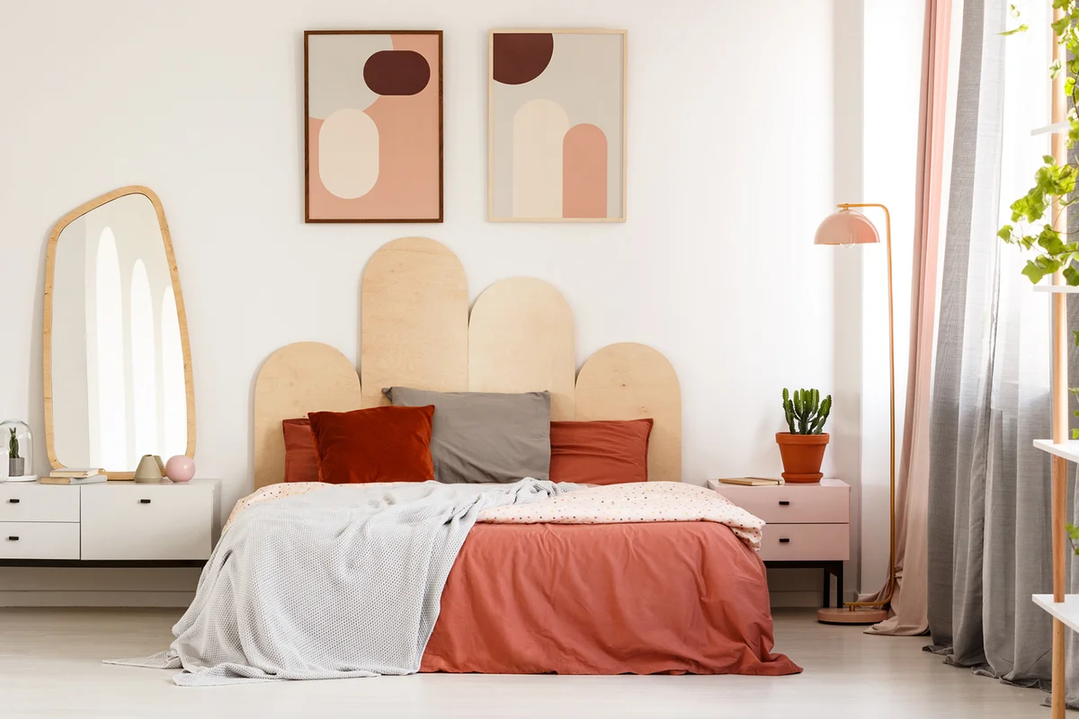 Modern posters above bed with headboard in pastel bedroom interior with mirror