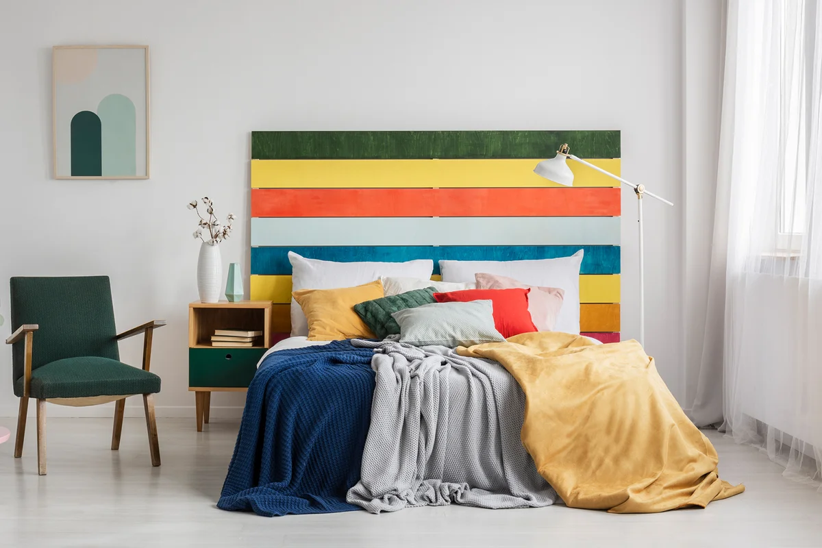 Retro armchair in modern bedroom interior with rainbow colored headboard