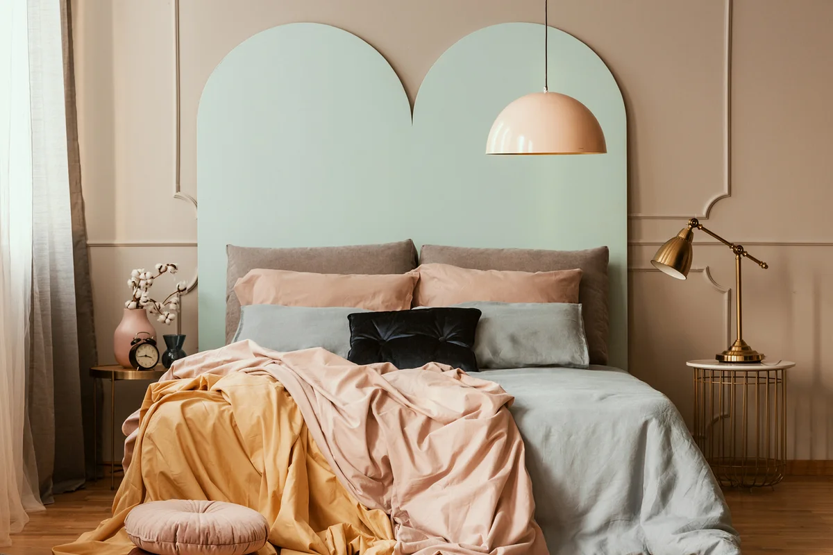 Pastel blue, pink and orange bedding on double bed in chic bedroom interior