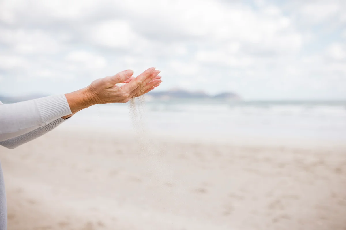 Woman's hand scattering ashes at beach