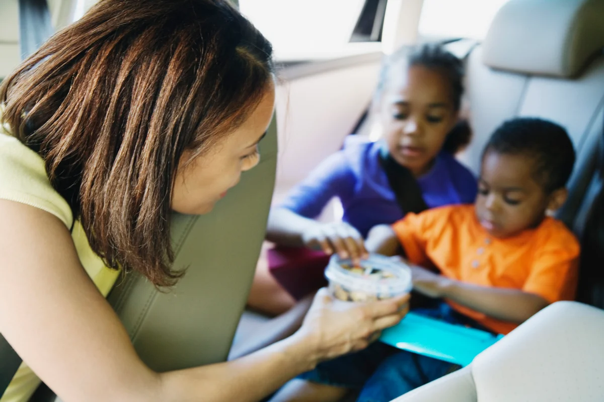 Mom helping her kids settle in the car and giving them snacks