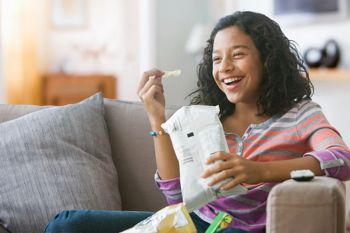 girl eating potato chips on sofa