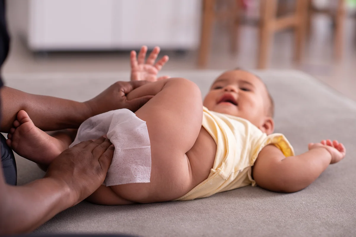 Mom wiping baby's bottom with baby wipe