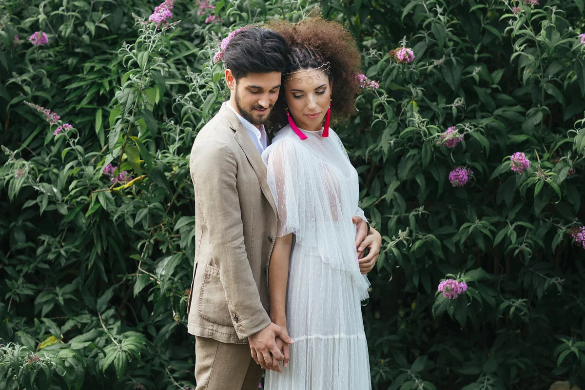 Loving couple embracing while standing against flowering plant