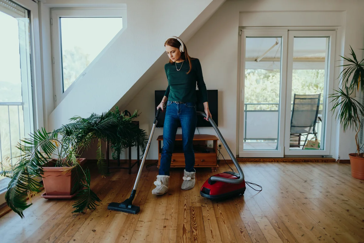 woman cleaning wood floors with vacuum